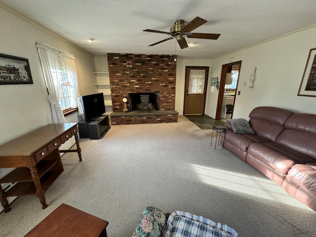 carpeted living room featuring ceiling fan, a fireplace, ornamental molding, and a textured ceiling