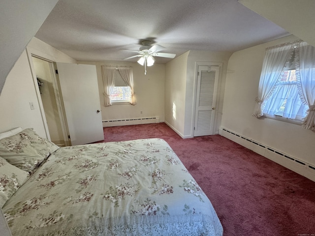 carpeted bedroom with ceiling fan, multiple windows, and a baseboard heating unit