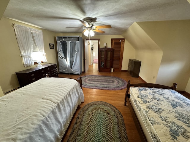 bedroom featuring a textured ceiling, light hardwood / wood-style floors, ceiling fan, and lofted ceiling