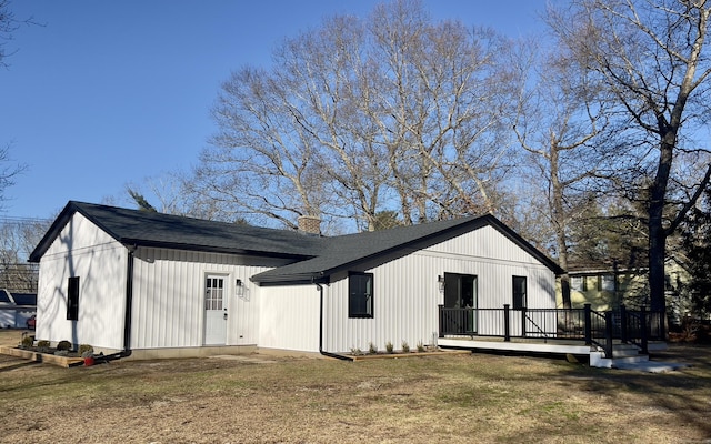 rear view of house featuring a lawn and a deck