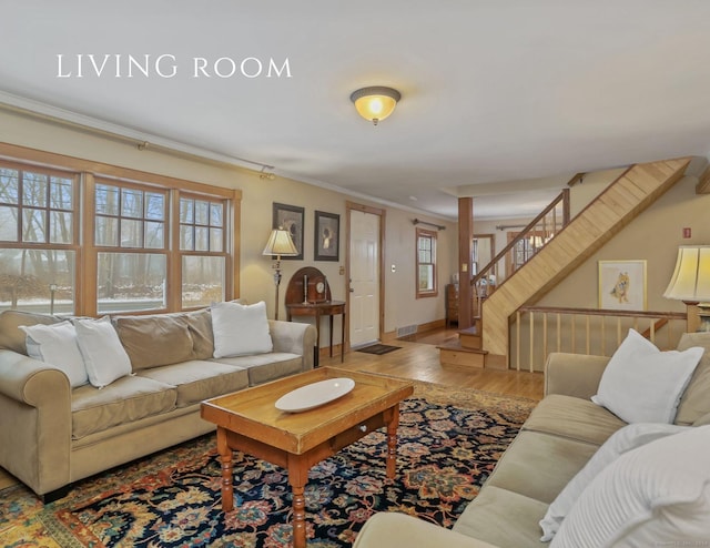 living room featuring light hardwood / wood-style floors, crown molding, and a wealth of natural light