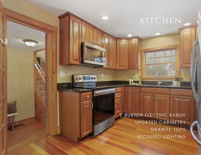 kitchen featuring dark stone countertops, stainless steel appliances, light hardwood / wood-style floors, and sink