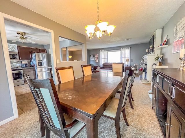 carpeted dining room with ceiling fan with notable chandelier, a textured ceiling, and a fireplace