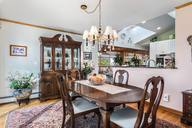 dining room with vaulted ceiling, ornamental molding, a notable chandelier, and light wood-type flooring