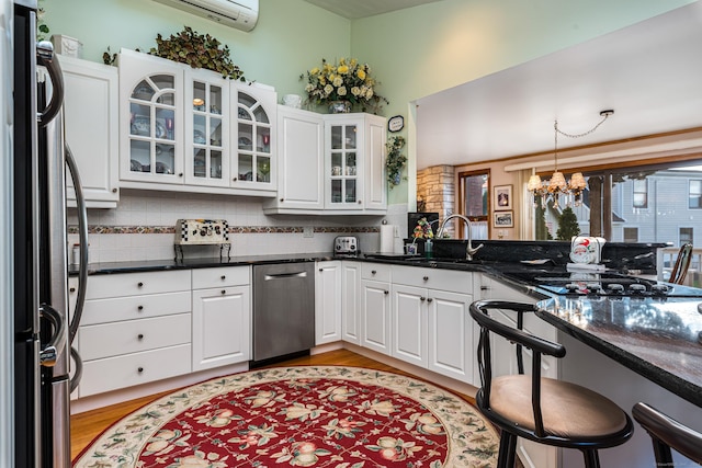 kitchen featuring stainless steel refrigerator, sink, white cabinets, and hanging light fixtures