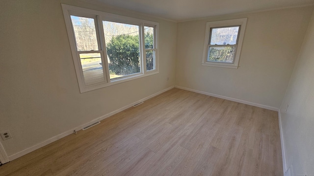 empty room with light wood-type flooring and crown molding