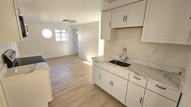 kitchen featuring white cabinetry, light stone countertops, sink, light hardwood / wood-style floors, and range