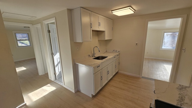 kitchen with white cabinets, light hardwood / wood-style floors, a wealth of natural light, and sink