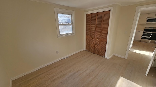 unfurnished bedroom featuring a closet, light hardwood / wood-style flooring, and crown molding