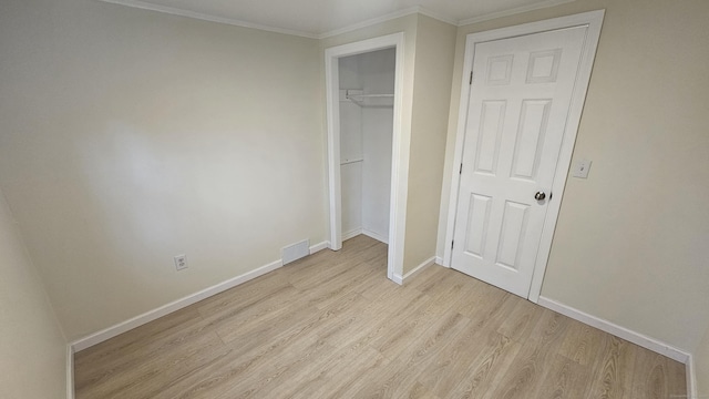 unfurnished bedroom with light hardwood / wood-style flooring, a closet, and crown molding