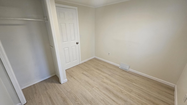 unfurnished bedroom with a closet, crown molding, and light hardwood / wood-style flooring