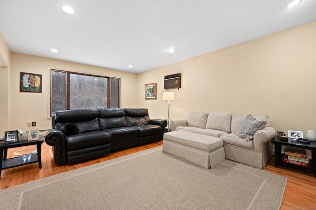 living room featuring a wall mounted air conditioner and light hardwood / wood-style flooring