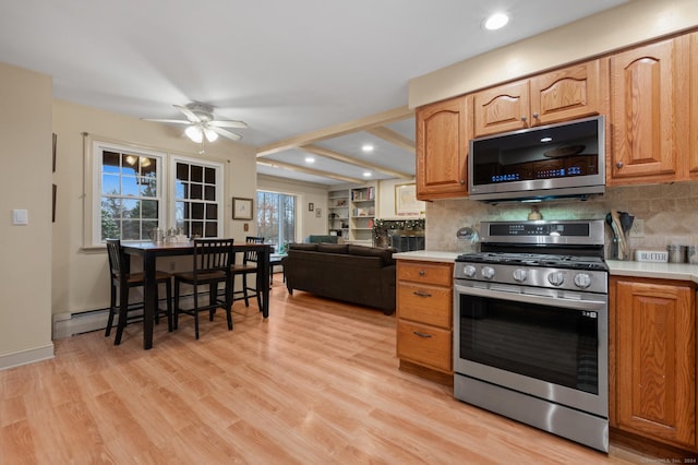 kitchen featuring decorative backsplash, appliances with stainless steel finishes, light wood-type flooring, and ceiling fan