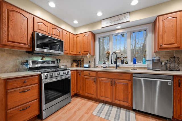 kitchen featuring backsplash, light wood-type flooring, sink, and appliances with stainless steel finishes