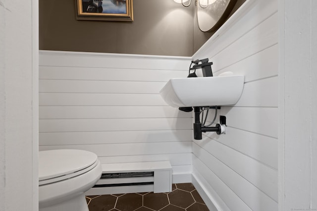 bathroom with sink, baseboard heating, tile patterned flooring, toilet, and wooden walls