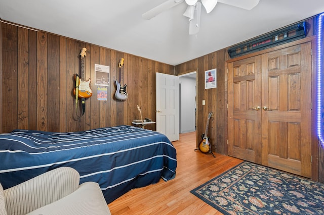 bedroom with wood walls, a closet, ceiling fan, and hardwood / wood-style flooring