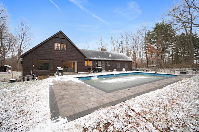 snow covered pool with grilling area and a patio