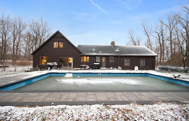 snow covered pool featuring a diving board and a patio