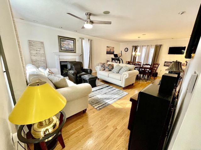 living room with ceiling fan, ornamental molding, and light hardwood / wood-style floors