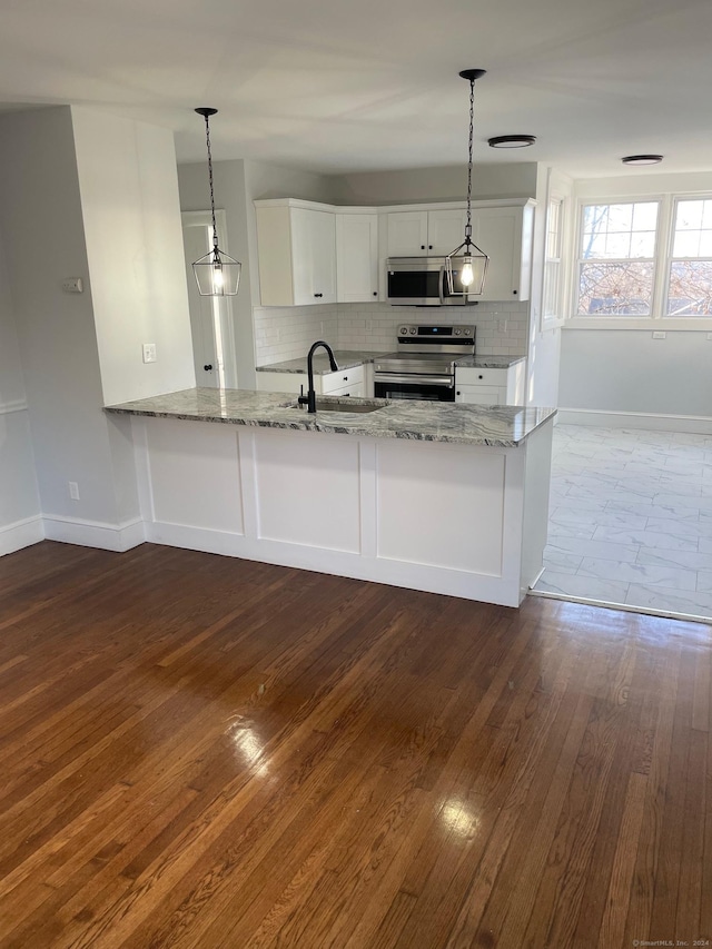 kitchen featuring white cabinets, decorative light fixtures, kitchen peninsula, and appliances with stainless steel finishes