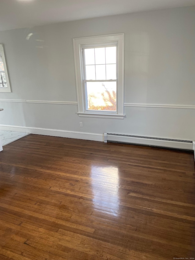 empty room with dark hardwood / wood-style flooring and a baseboard radiator