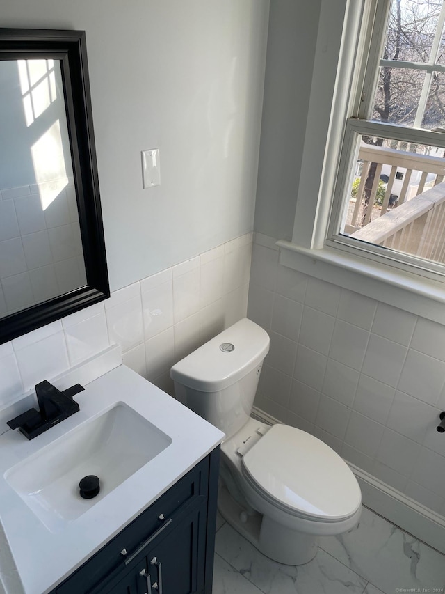 bathroom featuring vanity, tile walls, and toilet