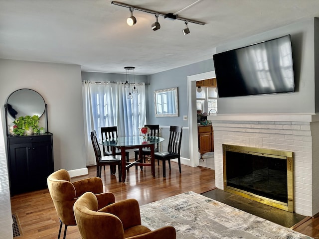 living room featuring dark hardwood / wood-style flooring, rail lighting, and a brick fireplace