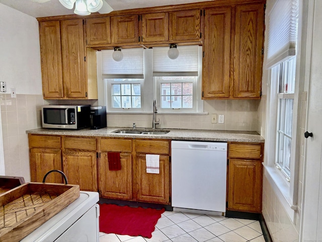 kitchen featuring white dishwasher, backsplash, light tile patterned floors, and sink