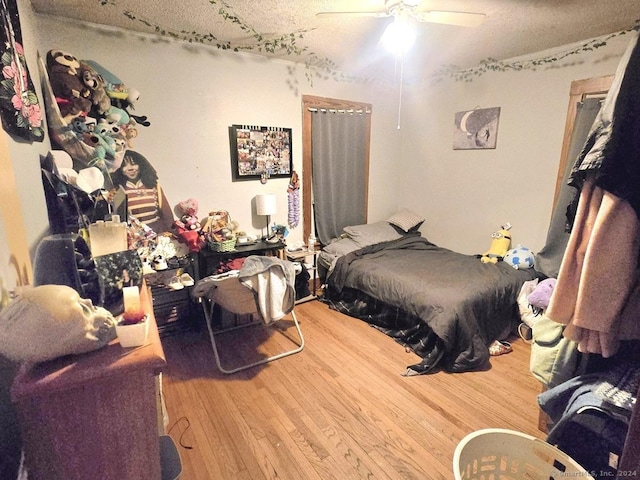 bedroom with ceiling fan, wood-type flooring, and a textured ceiling