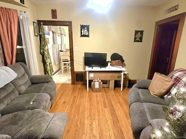 living room with a baseboard heating unit and light hardwood / wood-style flooring