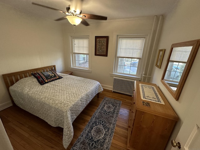 bedroom with ceiling fan, dark hardwood / wood-style floors, radiator, and multiple windows