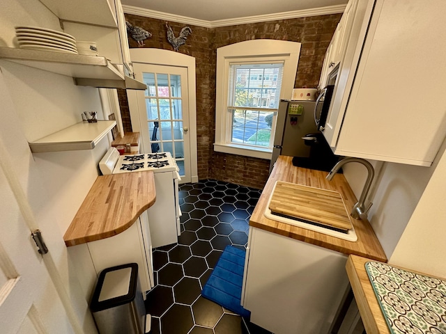 kitchen featuring wood counters, ornamental molding, brick wall, white range, and fridge