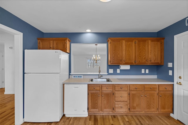 kitchen with decorative light fixtures, light hardwood / wood-style floors, white appliances, and sink