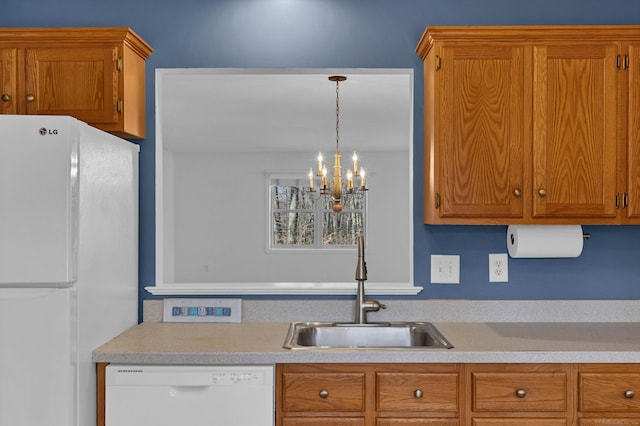 kitchen with sink, hanging light fixtures, white appliances, and an inviting chandelier