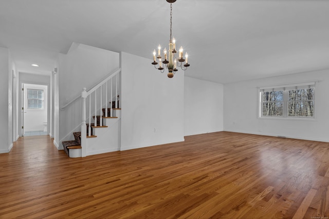 unfurnished living room featuring a chandelier and hardwood / wood-style floors