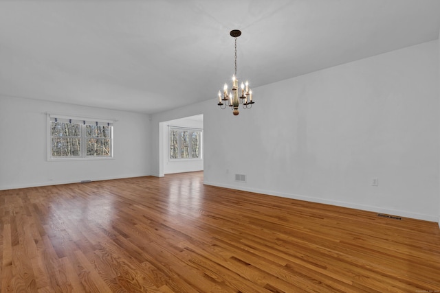 unfurnished room featuring a chandelier and light wood-type flooring