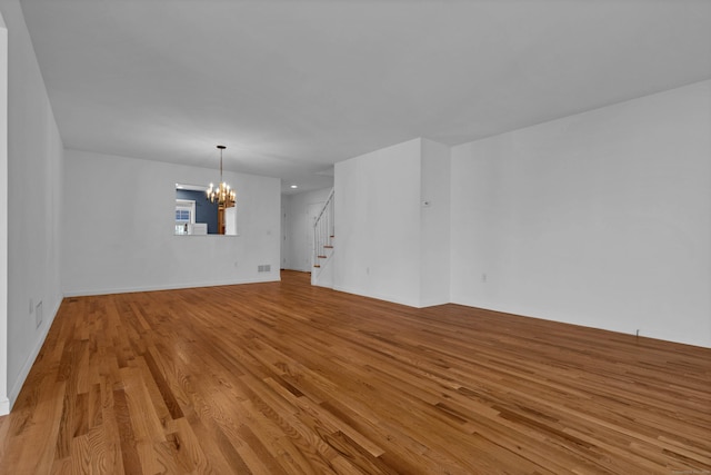 empty room featuring an inviting chandelier and light hardwood / wood-style flooring