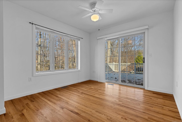 spare room with ceiling fan, light wood-type flooring, and a wealth of natural light