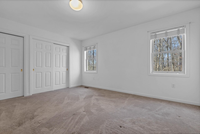 unfurnished bedroom with light colored carpet and multiple closets