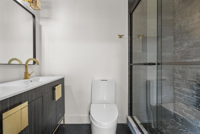 bathroom featuring toilet, vanity, and a shower with shower door