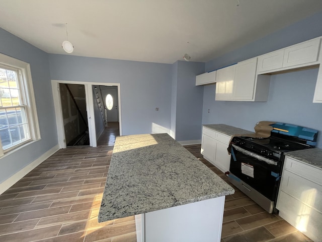 kitchen featuring white cabinetry, light stone countertops, a kitchen island, wood-type flooring, and range with gas cooktop