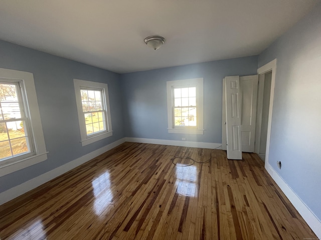 unfurnished bedroom with multiple windows and hardwood / wood-style flooring