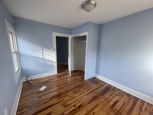 unfurnished bedroom featuring a closet and dark hardwood / wood-style floors