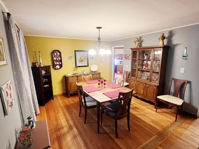 dining area with light hardwood / wood-style flooring, a notable chandelier, and crown molding