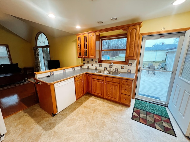 kitchen featuring sink, tasteful backsplash, kitchen peninsula, white dishwasher, and light colored carpet