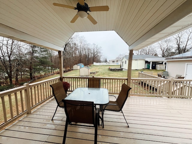 wooden deck with a lawn, ceiling fan, and a shed