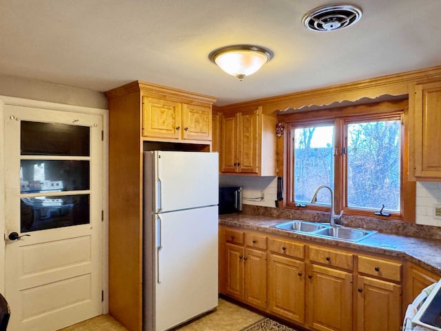 kitchen featuring backsplash, white refrigerator, stove, and sink