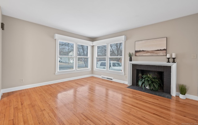 unfurnished living room with light hardwood / wood-style floors and a brick fireplace