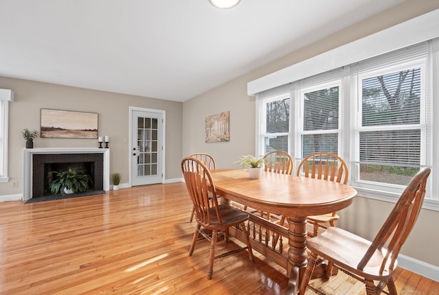 dining room featuring light wood-type flooring and a brick fireplace