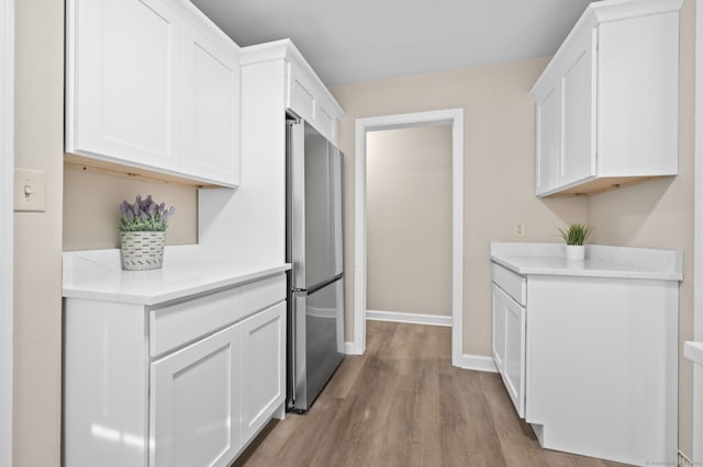 kitchen featuring stainless steel refrigerator, white cabinets, and light hardwood / wood-style floors